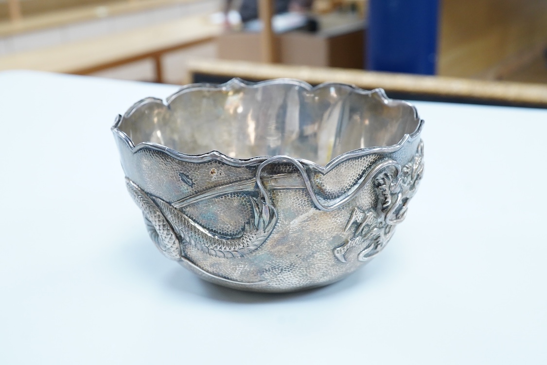 An early 20th century Japanese planished white metal double walled sugar bowl, decorated with the continuous scene of a dragon, signed to the base, diameter 12.1cm, 5.9oz(a.f.).